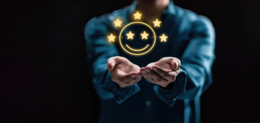 Man holding five stars and smiley face icon on dark background