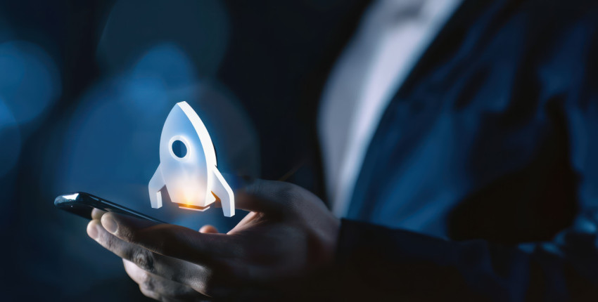 Businessman holding phone with rocket icon on the screen symbolizing startup launch