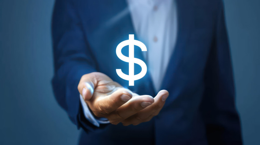 A businessman holding glowing dollar sign on blue background illustrating budget concept