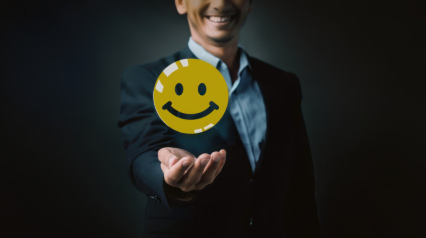 Businessman holding yellow smiley face icon illustrating feedback concept