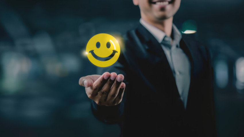 Businessman holding yellow smiley face icon with stars illustrating positive feedback concept in business