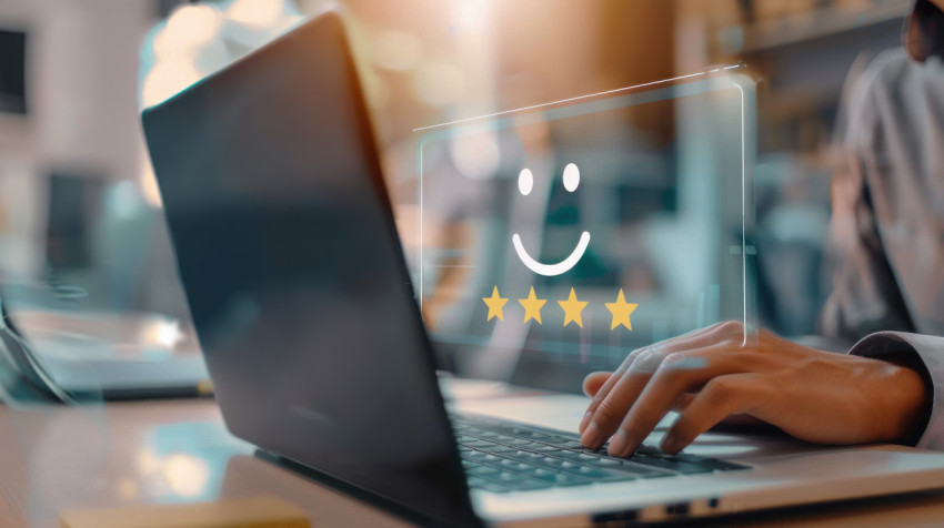 Person using laptop with virtual smiley face and four star icons showing customer satisfaction and positive feedback