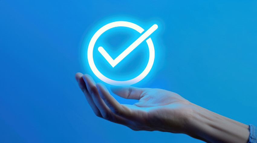 Hand holding check mark icon against blue background symbolizing business performance and checklist