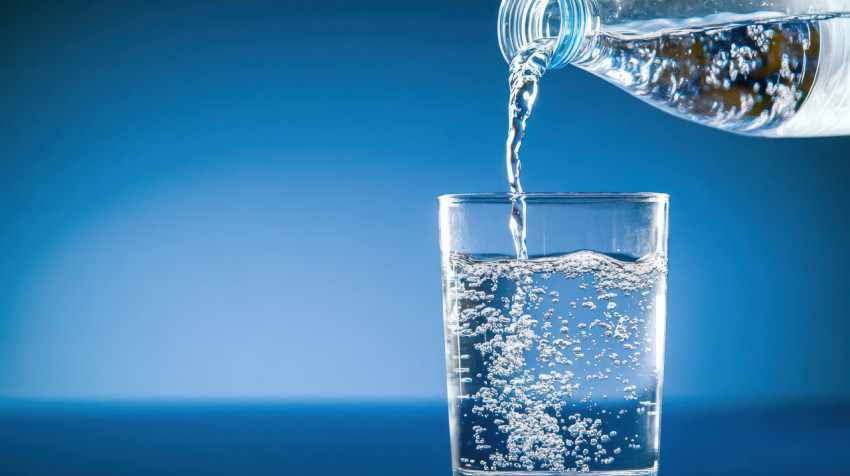 Water poured into glass with a blue background clean and simple