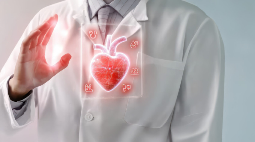 Doctor in white coat with stethoscope holds hand to digital heart on transparent screen