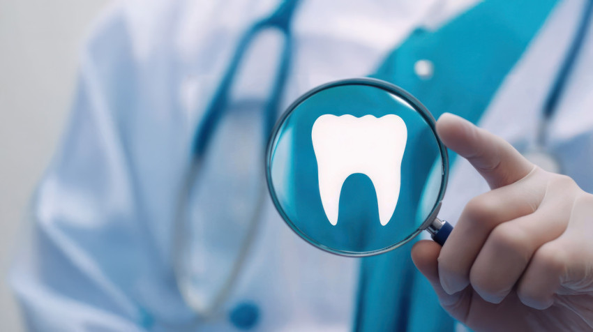 Dental doctor holds a magnifying glass with a tooth symbol on it against a professional medical background