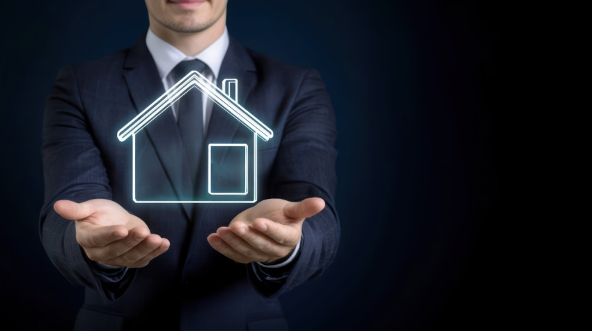 A businessman in a suit holding a glowing house icon on a dark blue background