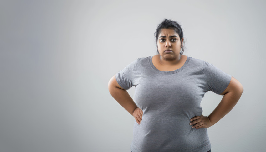 Chubby Indian woman standing with hands on hips looking stressed on a white background