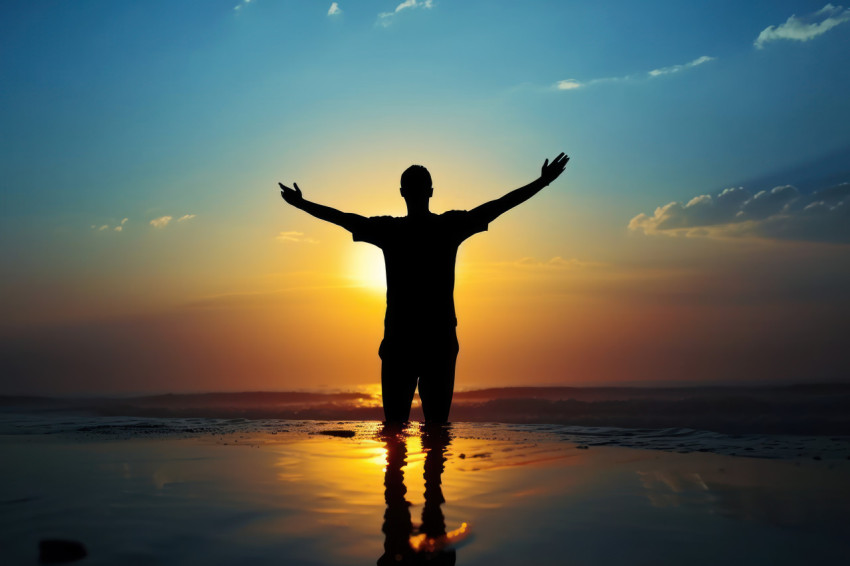 Man raises hands in joy as the sun rises embracing a new day with open arms