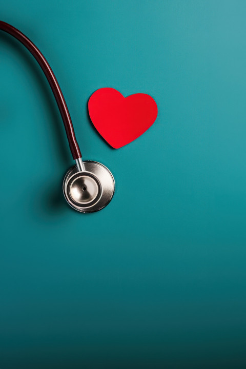 Stethoscope and dark red heart on a blue background emphasizing heart health
