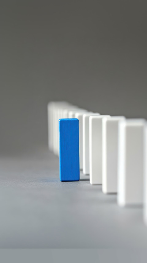 White domino line with one blue end piece set against a gray background job candidate idea