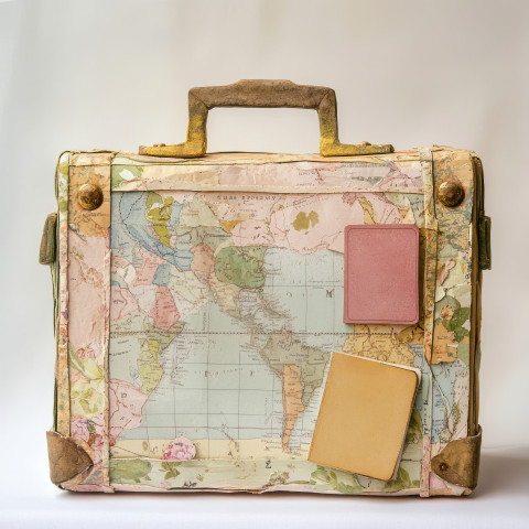 A vintage suitcase and passport on a map created from papier mache