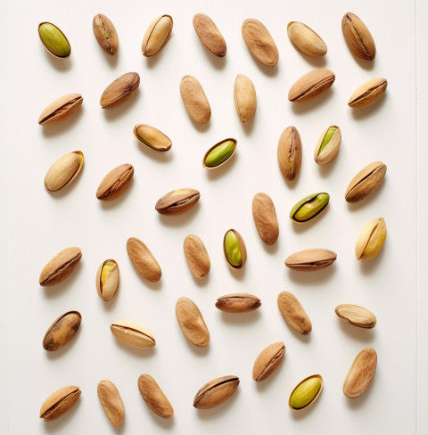 several pistachios on white wooden background